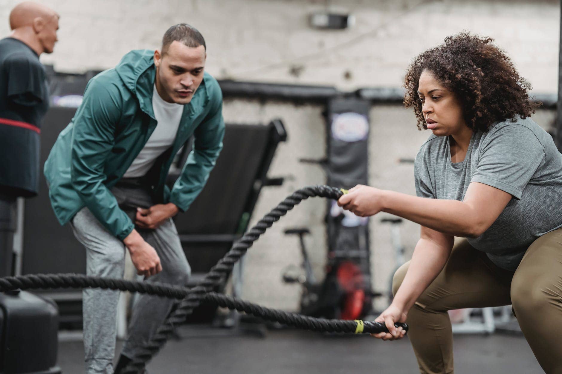 determined plump black woman exercising with battle ropes in gym