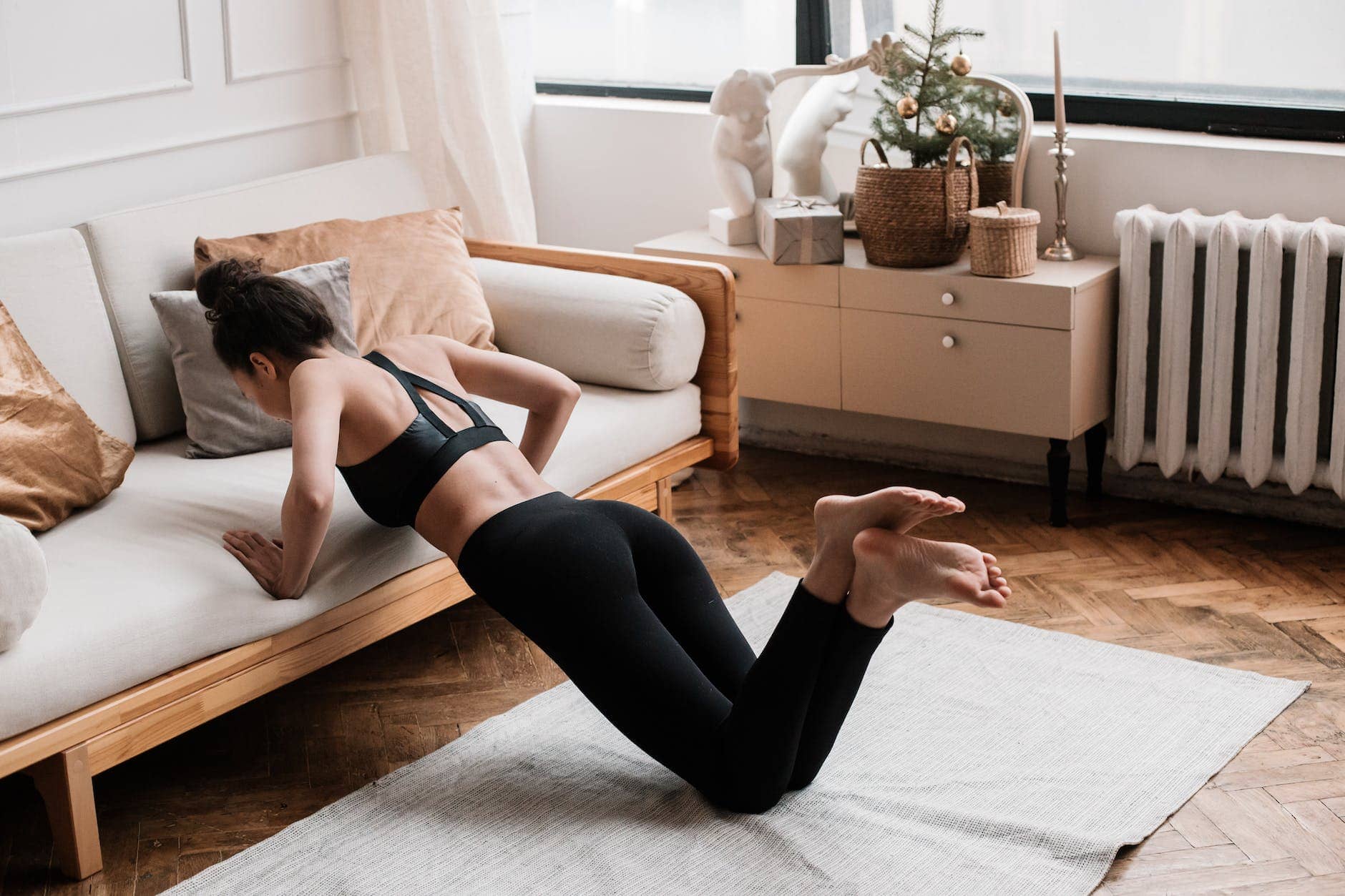young woman in black sports bra and black leggings doing home workout